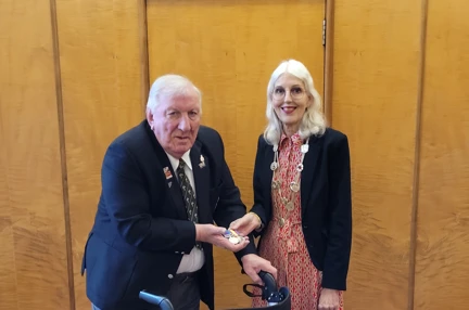 David wearing a suit jacket and his Blind Veterans UK pin badge is stood next to the Lord Mayor with the medal in David's hand