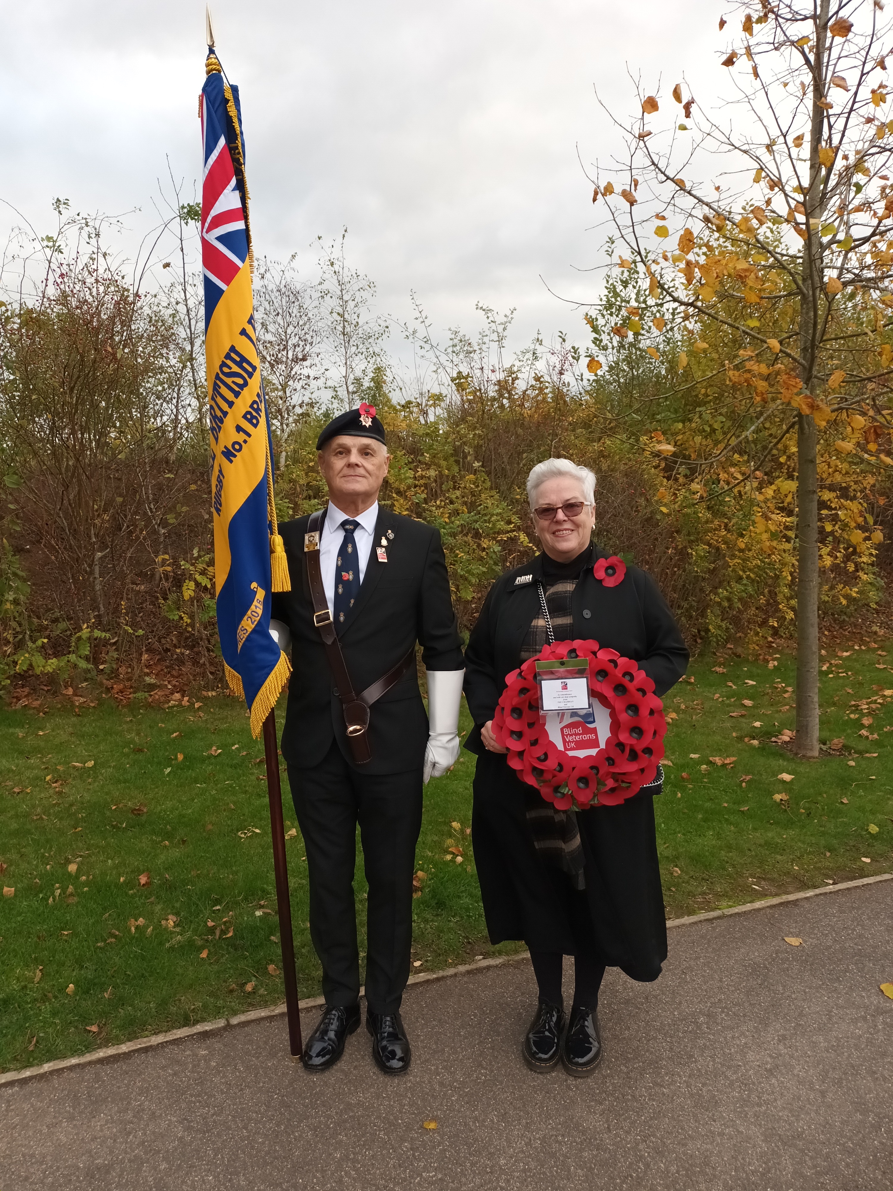 A photo of community support worker Anne (right) with blind veteran and standard bearer Wayne at the funeral of Geoffrey John Barker