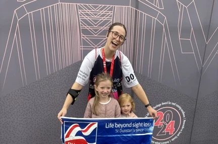 A picture of Hope with her two young nieces celebrating with a banner of Blind Veterans UK