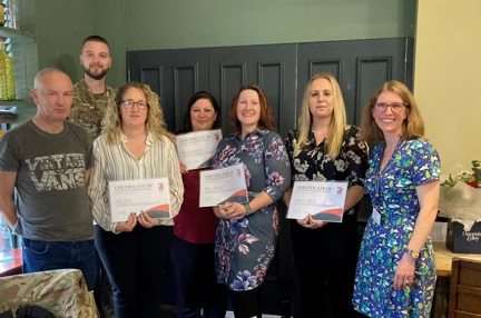 The four carers hold up their certificates. They are stood next to Corporal Chris Lake who had presented them.