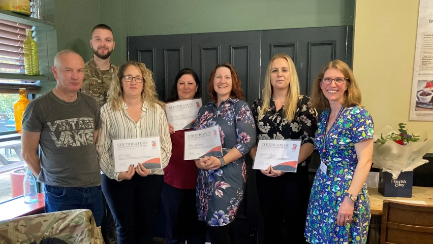 The four carers hold up their certificates. They are stood next to Corporal Chris Lake who had presented them.
