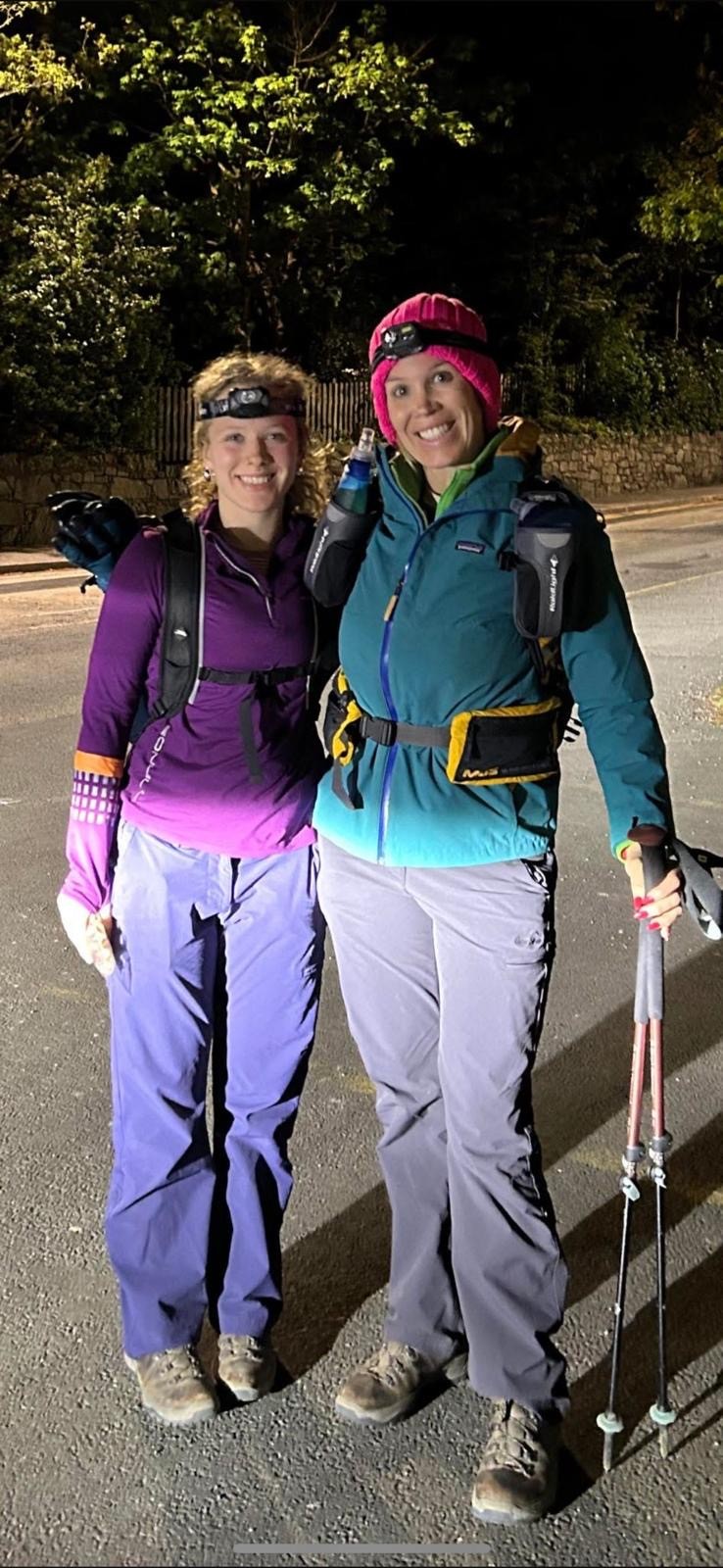 Anna and Rebecca in the dark wearing head torches and holding hiking sticks