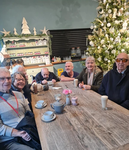 A group of people sit around a table drinking tea and coffee