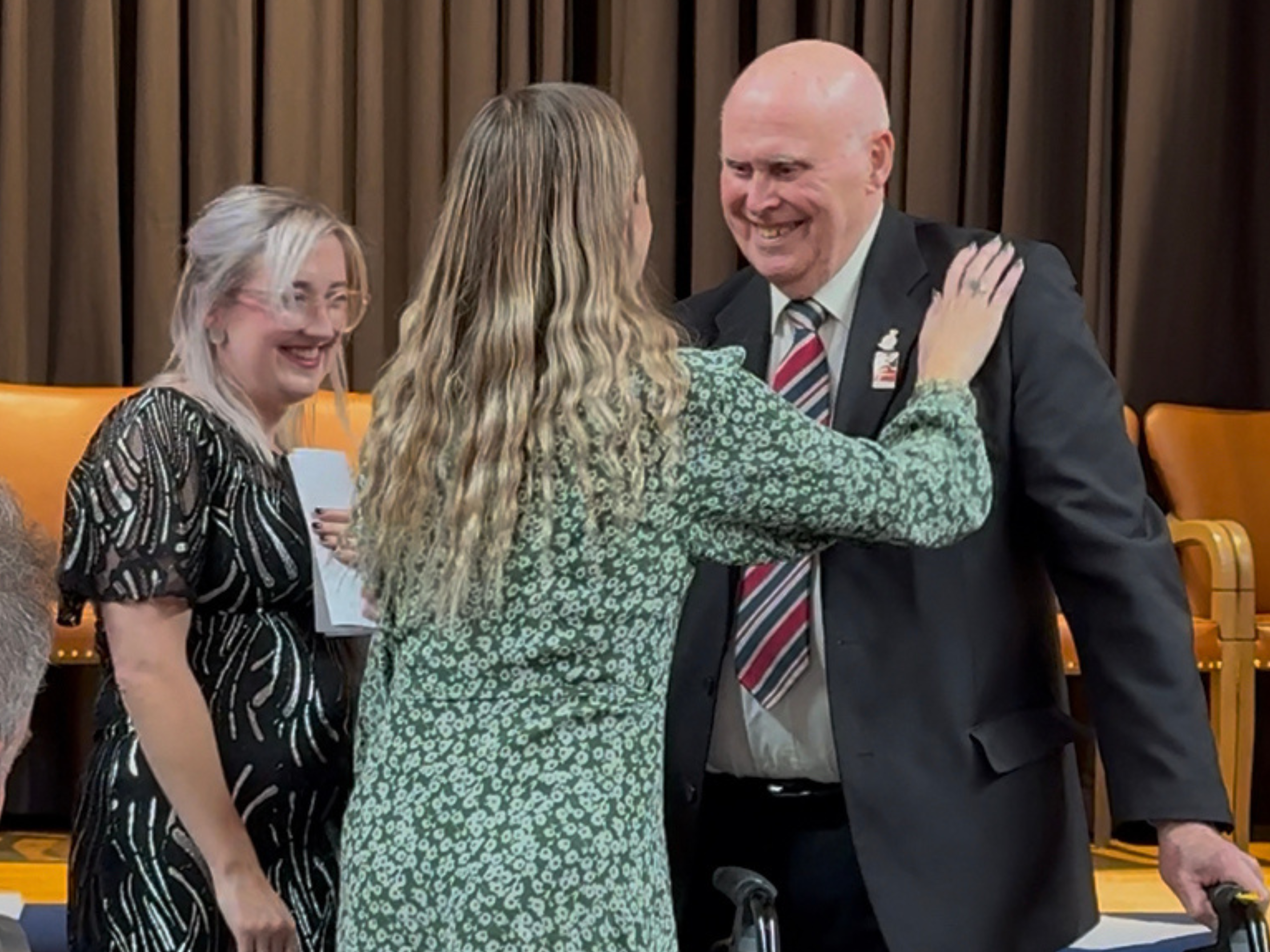 Lauren is presented with award by President Colin Williamson. Volunteer Coordinator Elaine and blind veteran Barry stand smiling next to them.