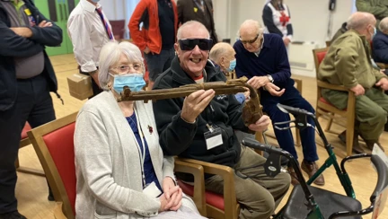 Photo of blind veteran Barry, right, and wife Joan, left, holding a gun during demonstration