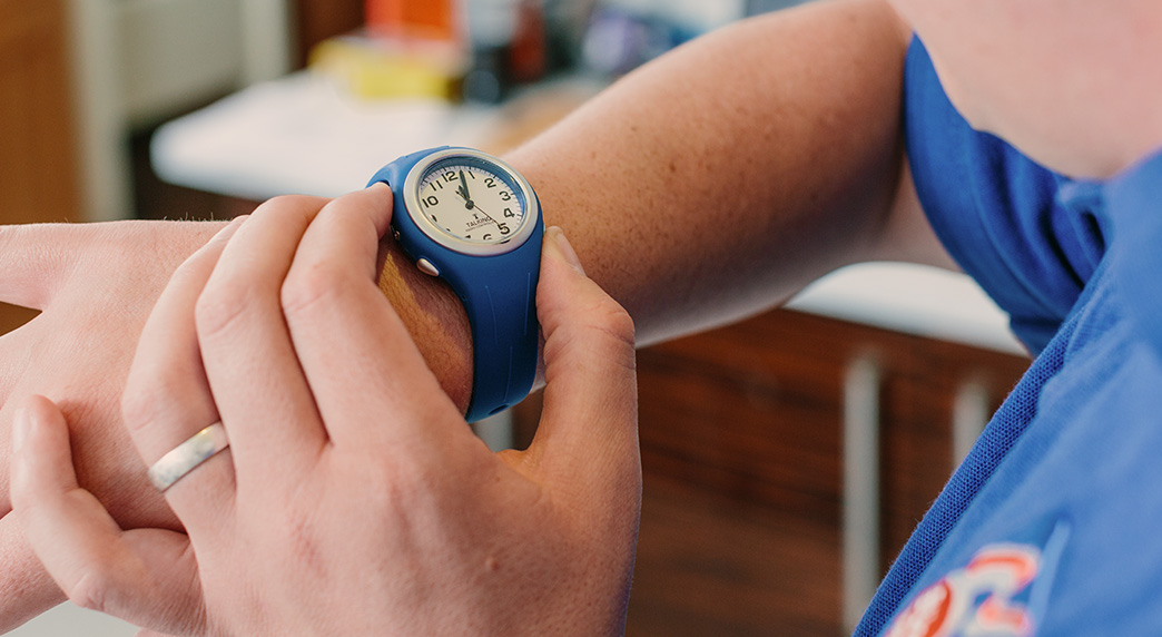 A close up of a blind veteran's wrist wearing a blue talking timer watch.