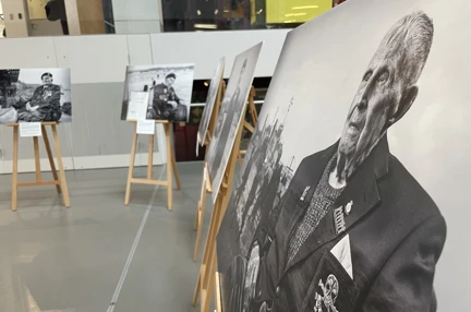 Five large black and white canvas images are displayed in a semi circle within a gallery space