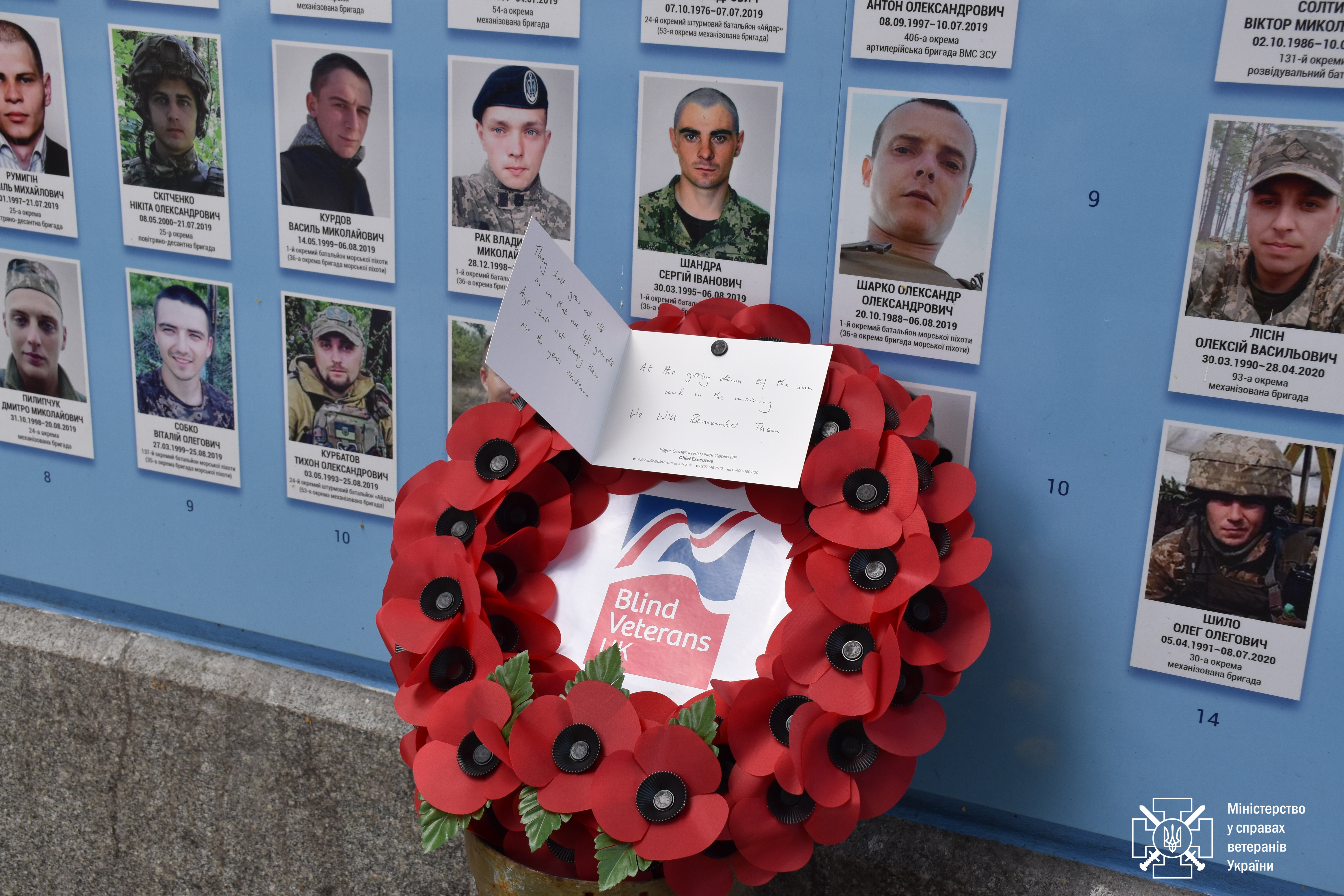 A Blind Veterans UK wreath and a written card, pictured laying next to portraits of Ukrainian solders