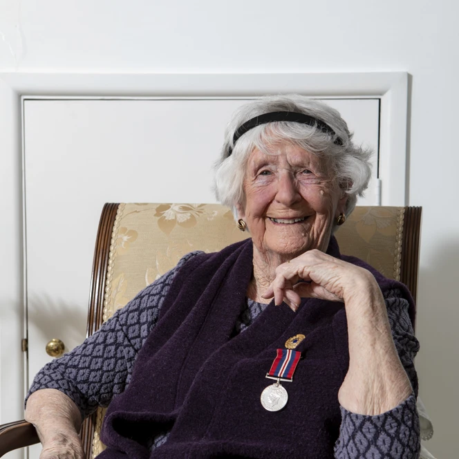 Blind veteran Alice posed sitting on a chair