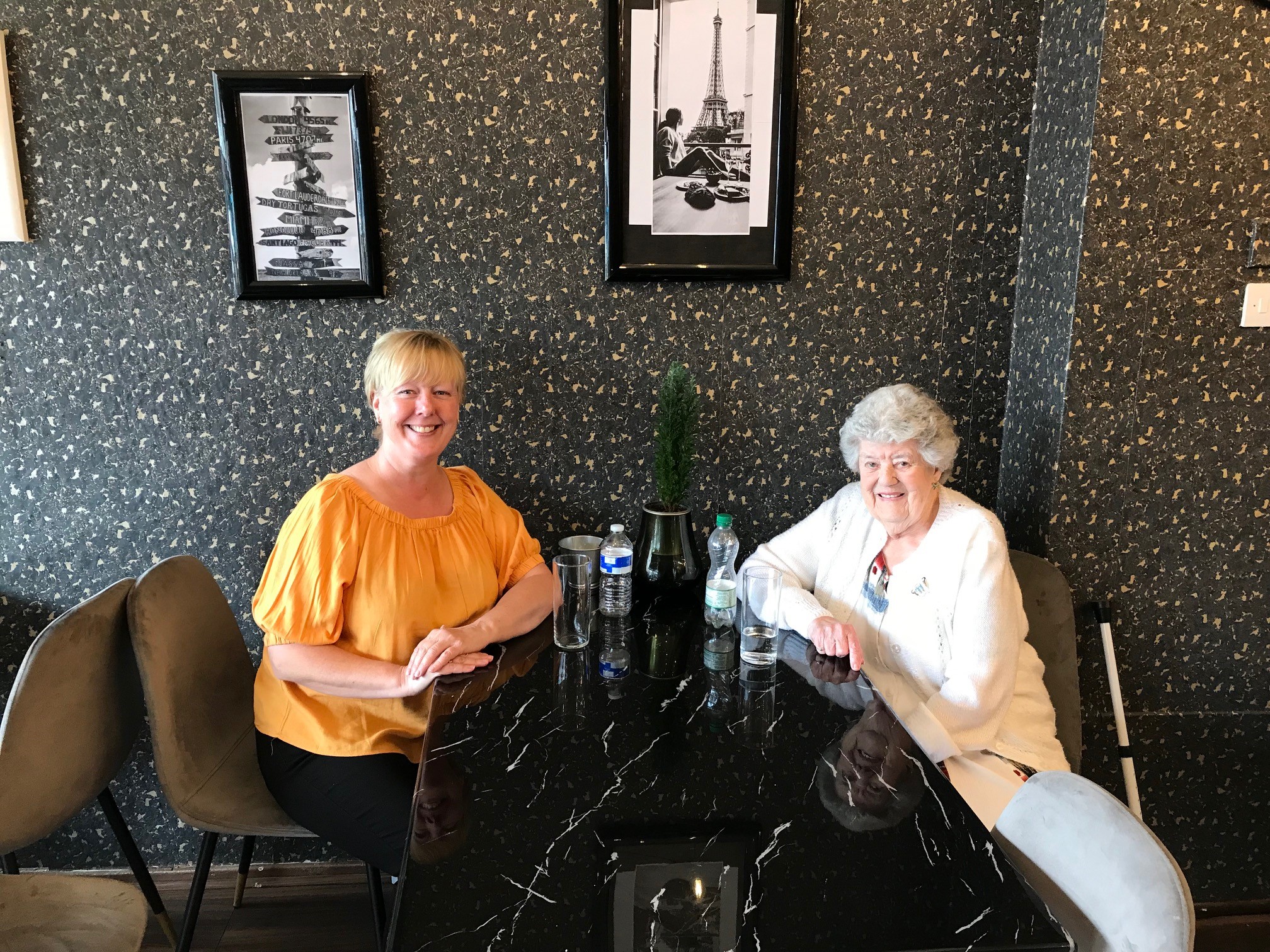 Chrissie and Lorna sat at a table in a restaurant, they are both smiling