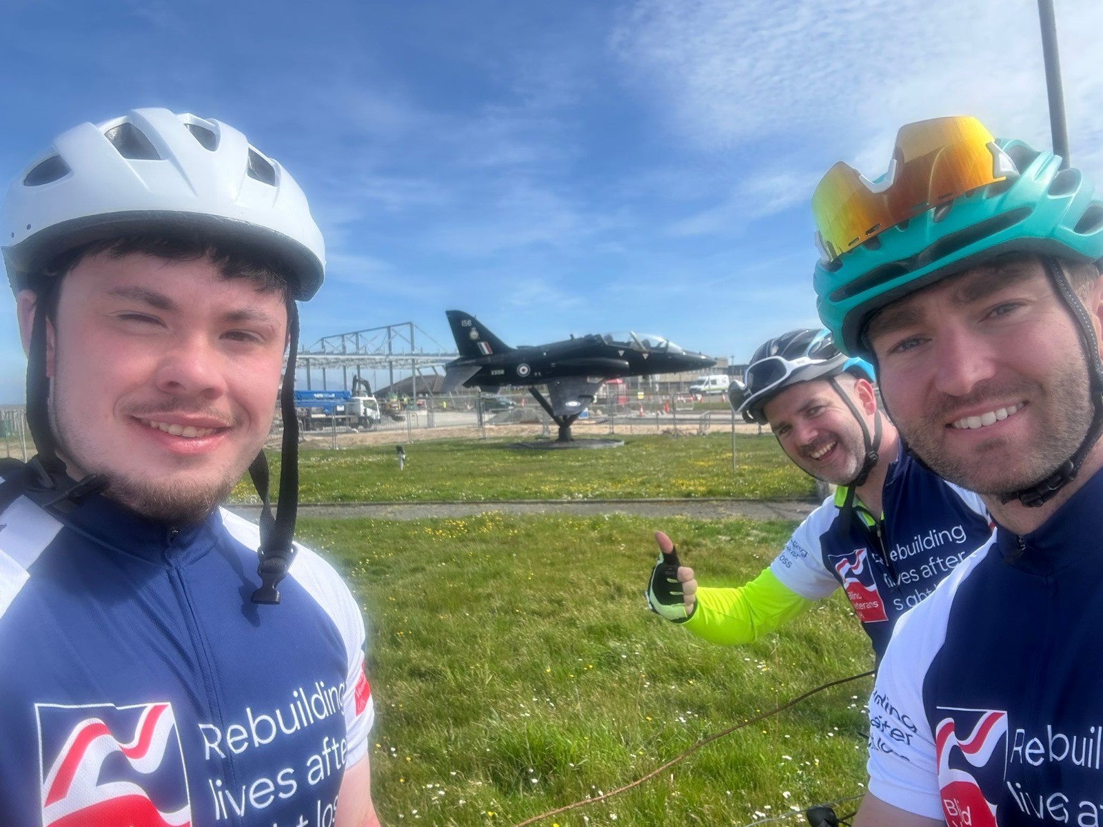 The three cyclists pose for a selfie in front of a hawk at RAF Valley