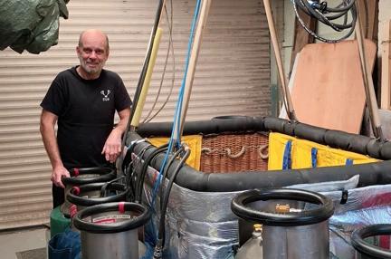 Blind veteran Mike stands next to the hot air balloon basket and gas canisters that will fuel his flight