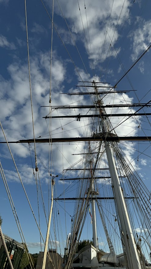 A photograph taken from the ground of Kelso up high on the mast, halfway along the yard arm