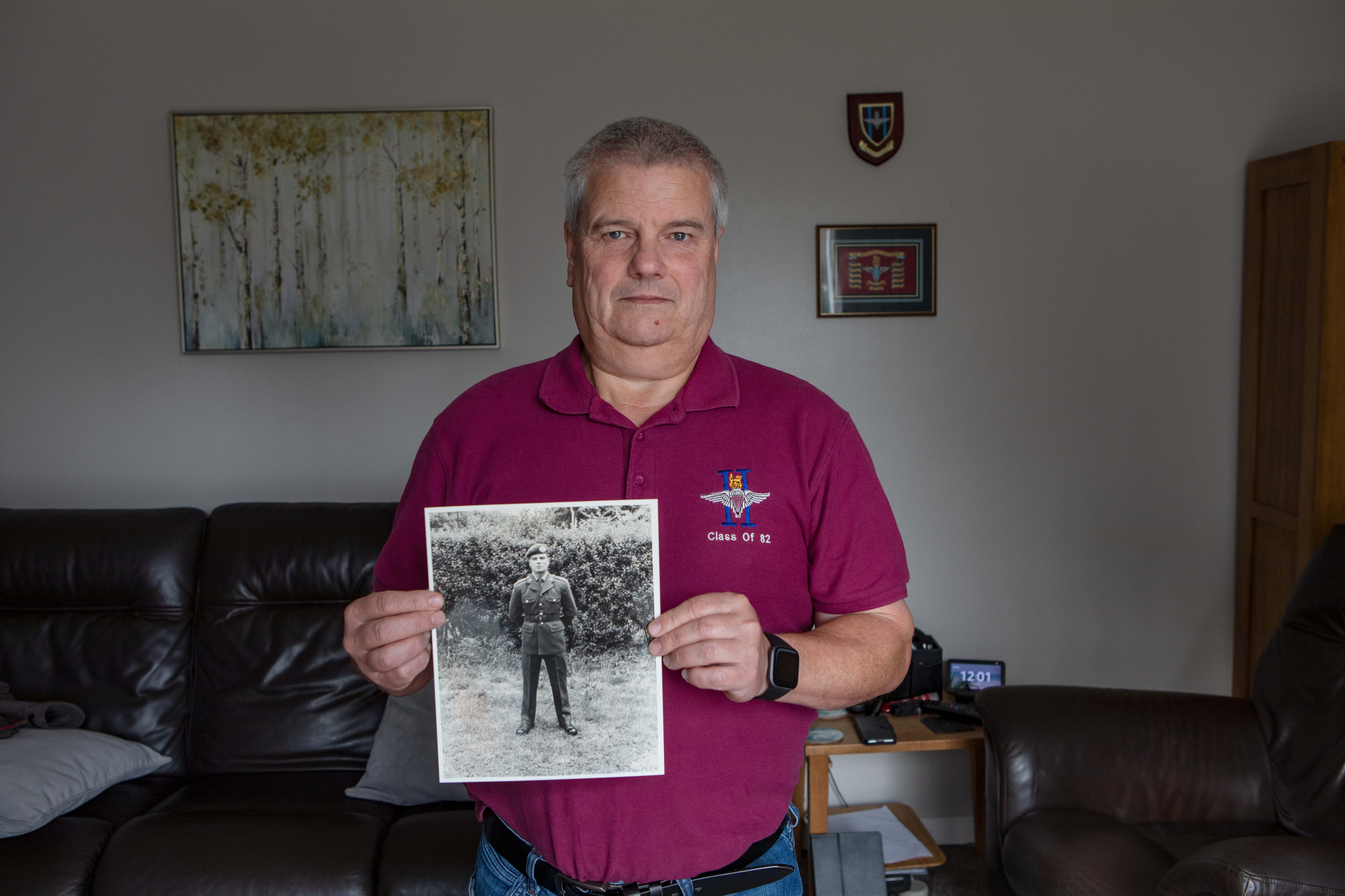 Blind veteran Steve holding a photo of him as a younger man in uniform