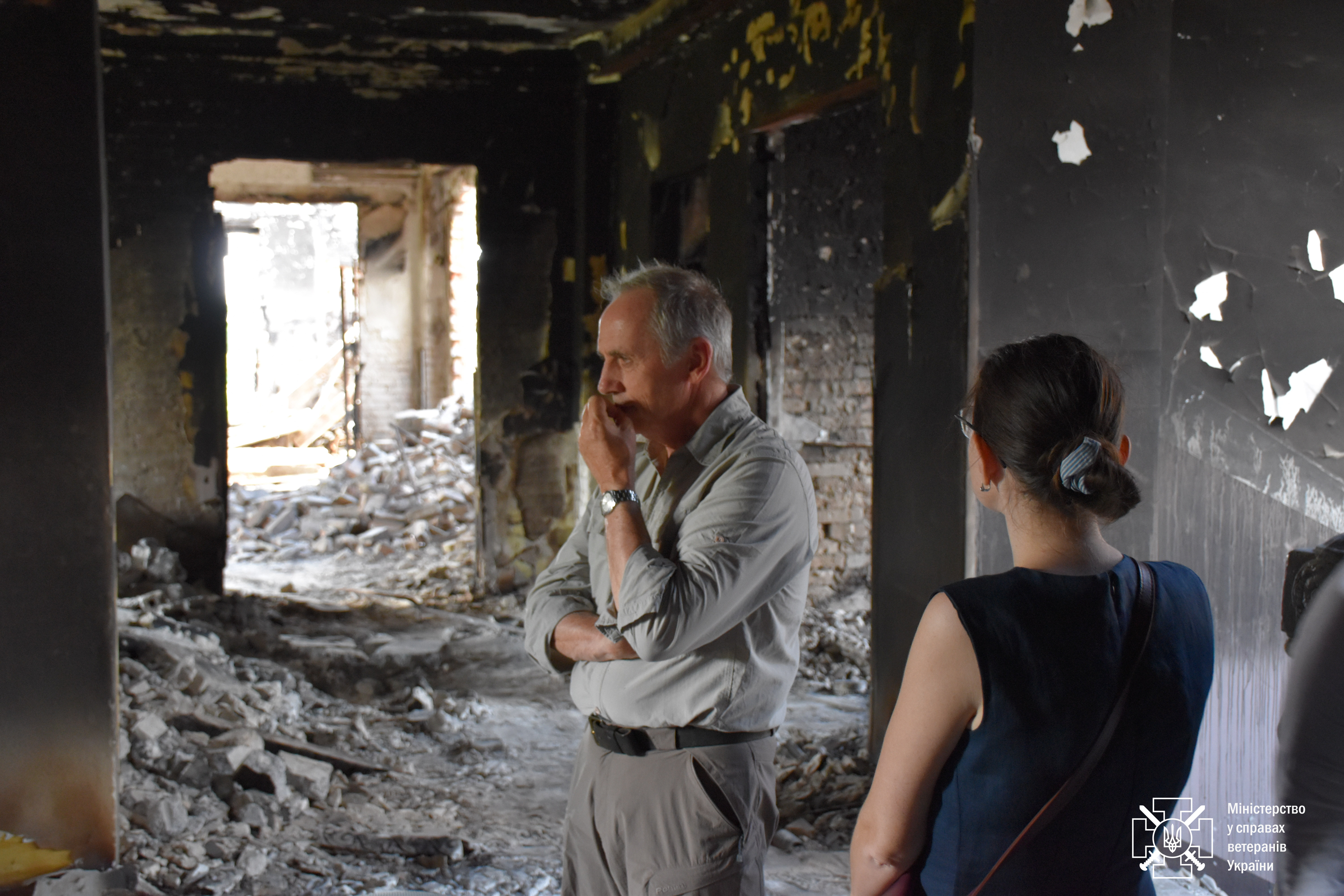 Nick Caplin is pictured with his hand to his mouth, looking pensive as he stands in a destroyed building in Ukraine