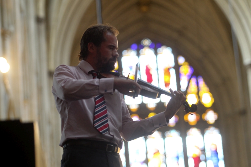 Composer Alastair Caplin playing a violin inside a church