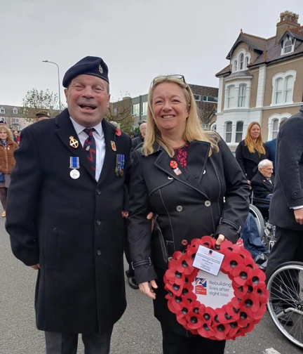 Billy and Kathy both smiling stood arm in arm holding the wreath