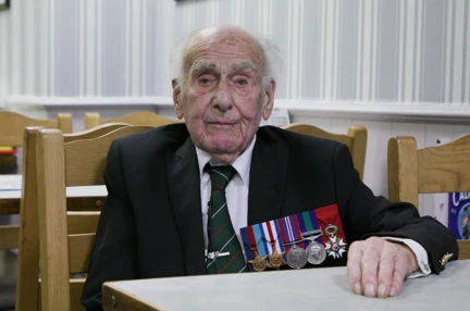 A photo of Blind veteran Harry sitting at a table during an interview