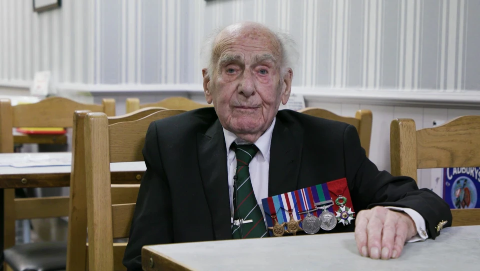 A photo of Blind veteran Harry sitting at a table during an interview