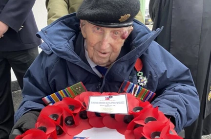 Ken in his beret and holding a poppy wreath